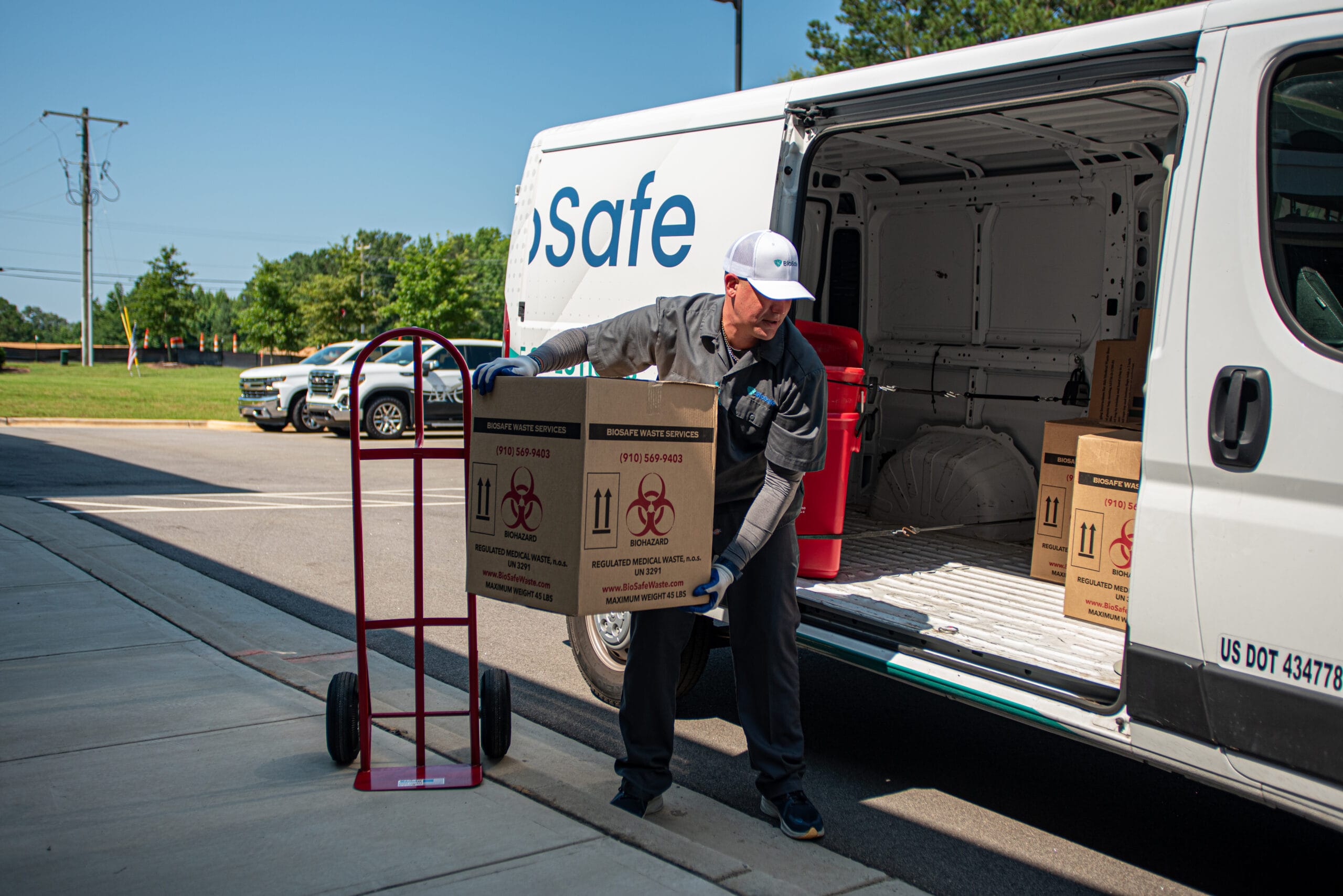 BioSafe technician loading regulated medical waste boxes into a service van