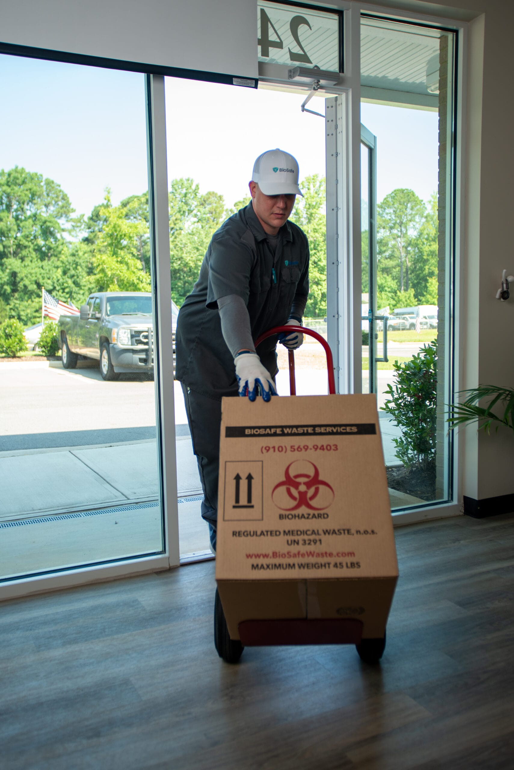 BioSafe technician wheeling a regulated medical waste box into a facility on a hand truck