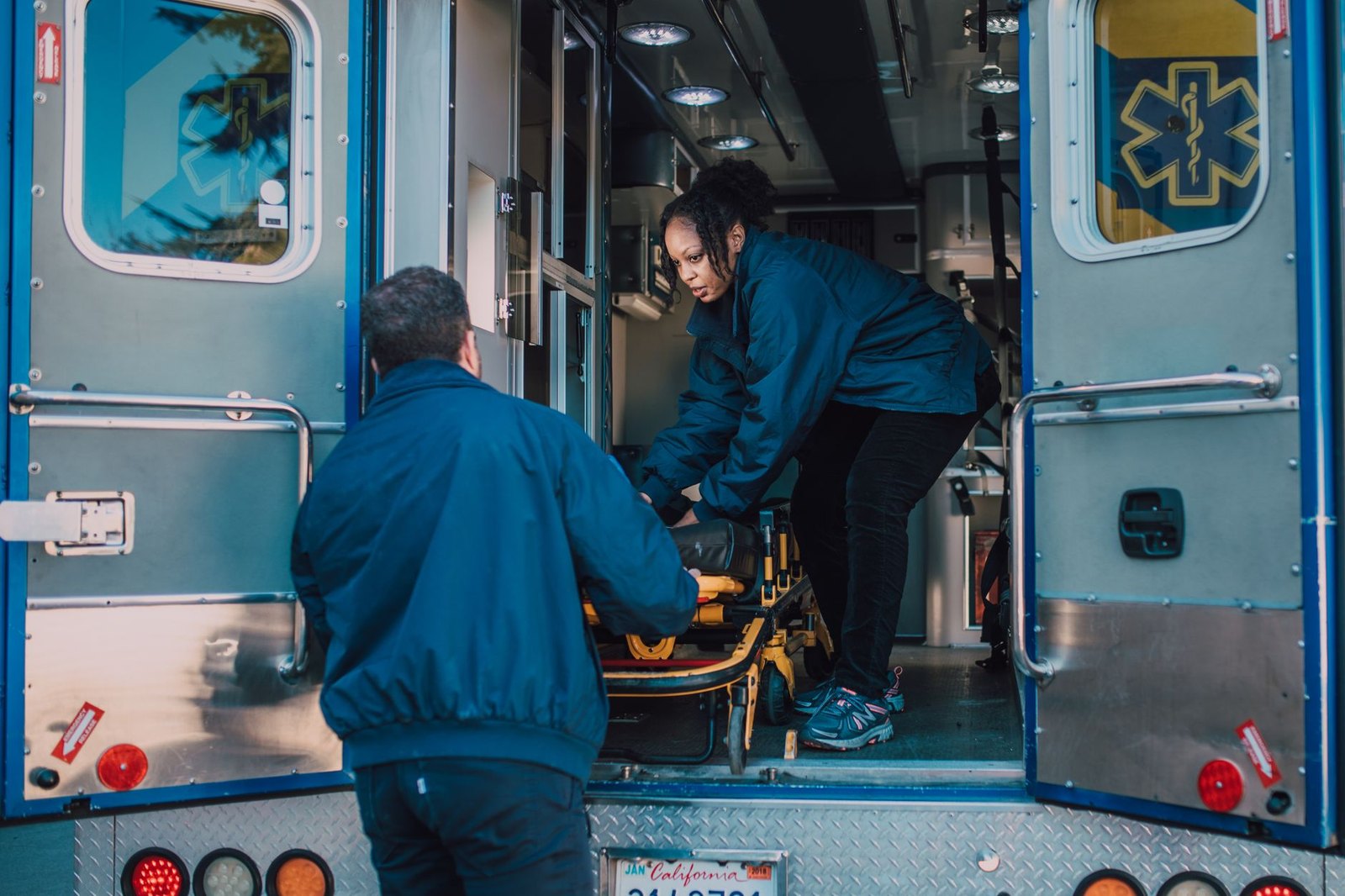 Paramedics loading a stretcher into an ambulance