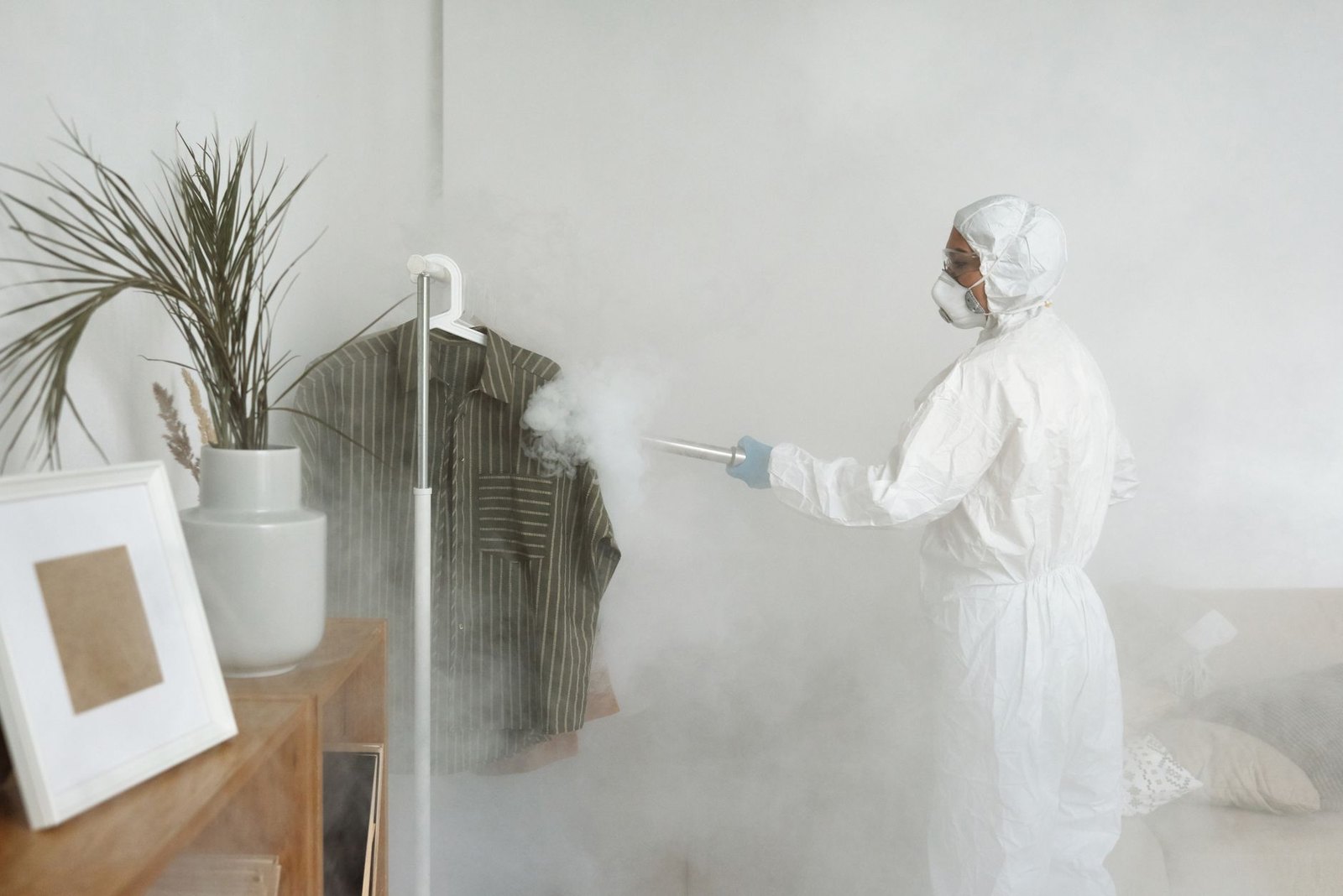 Worker in full protective gear decontaminating an interior space